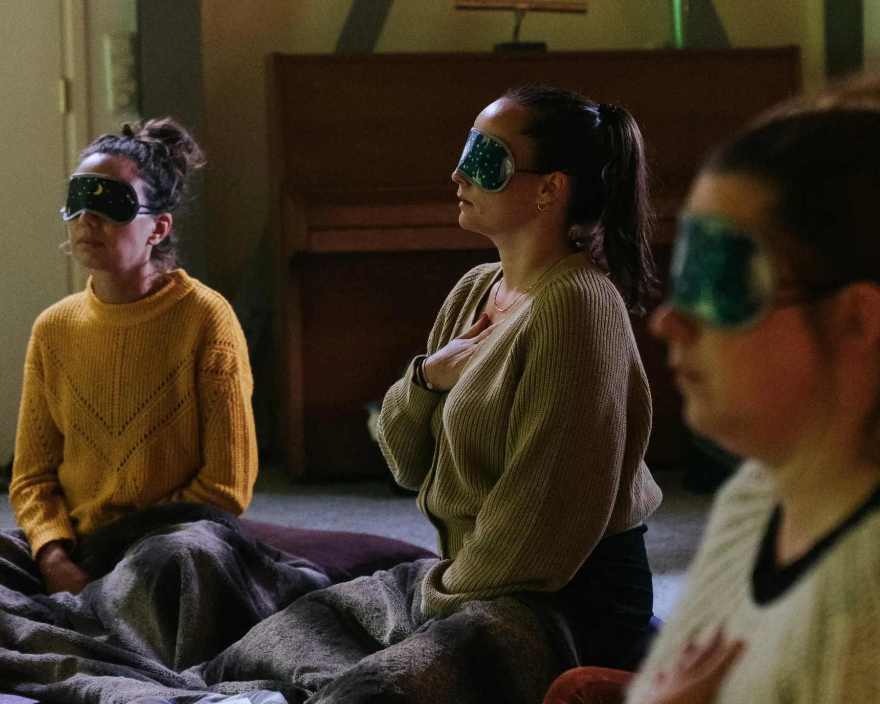 Deelnemers met oogmaskers en een hand op het hart tijdens de ademcirkel