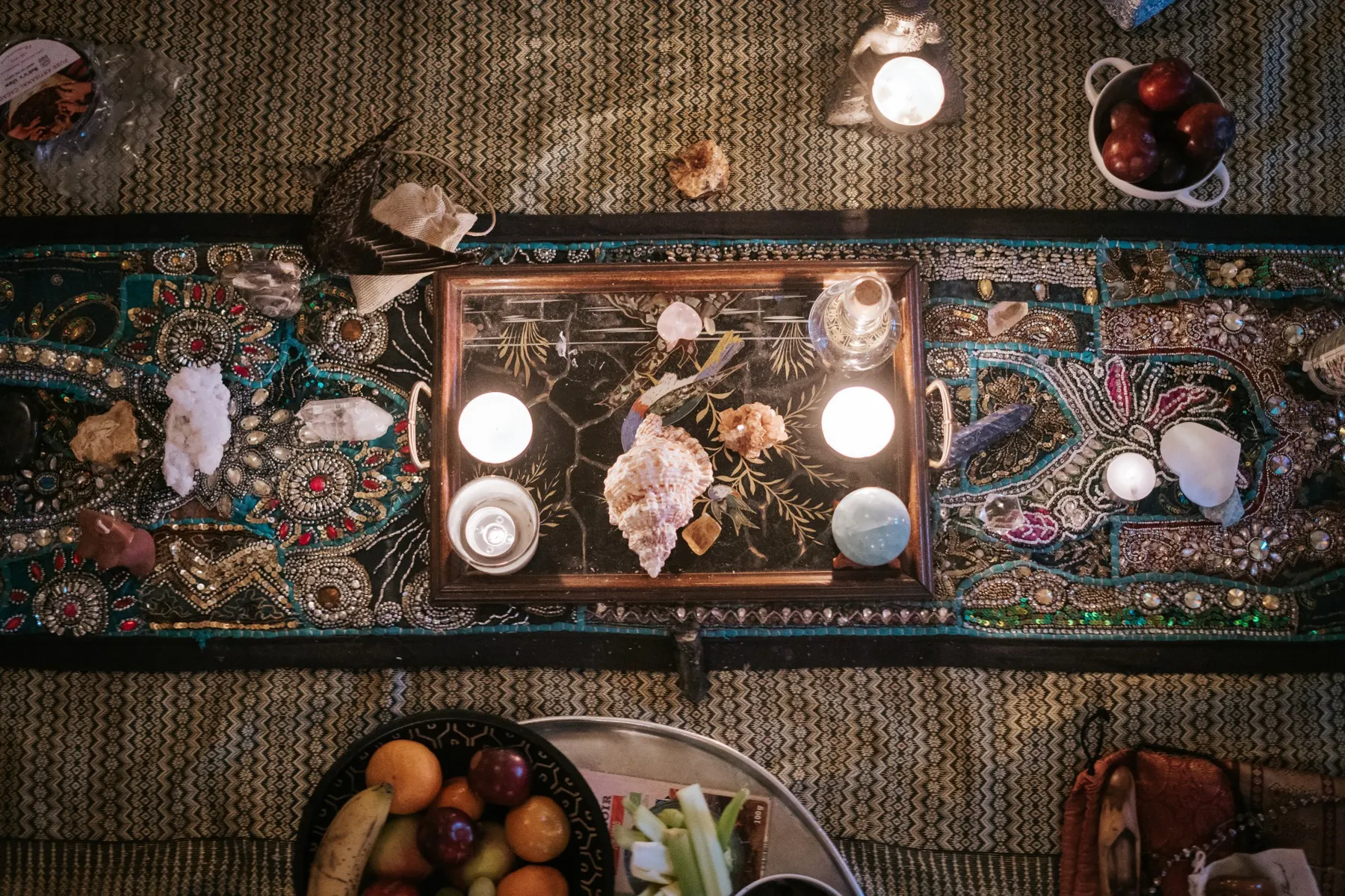 An altar seen from above: candles and shells on an embroidered cloth