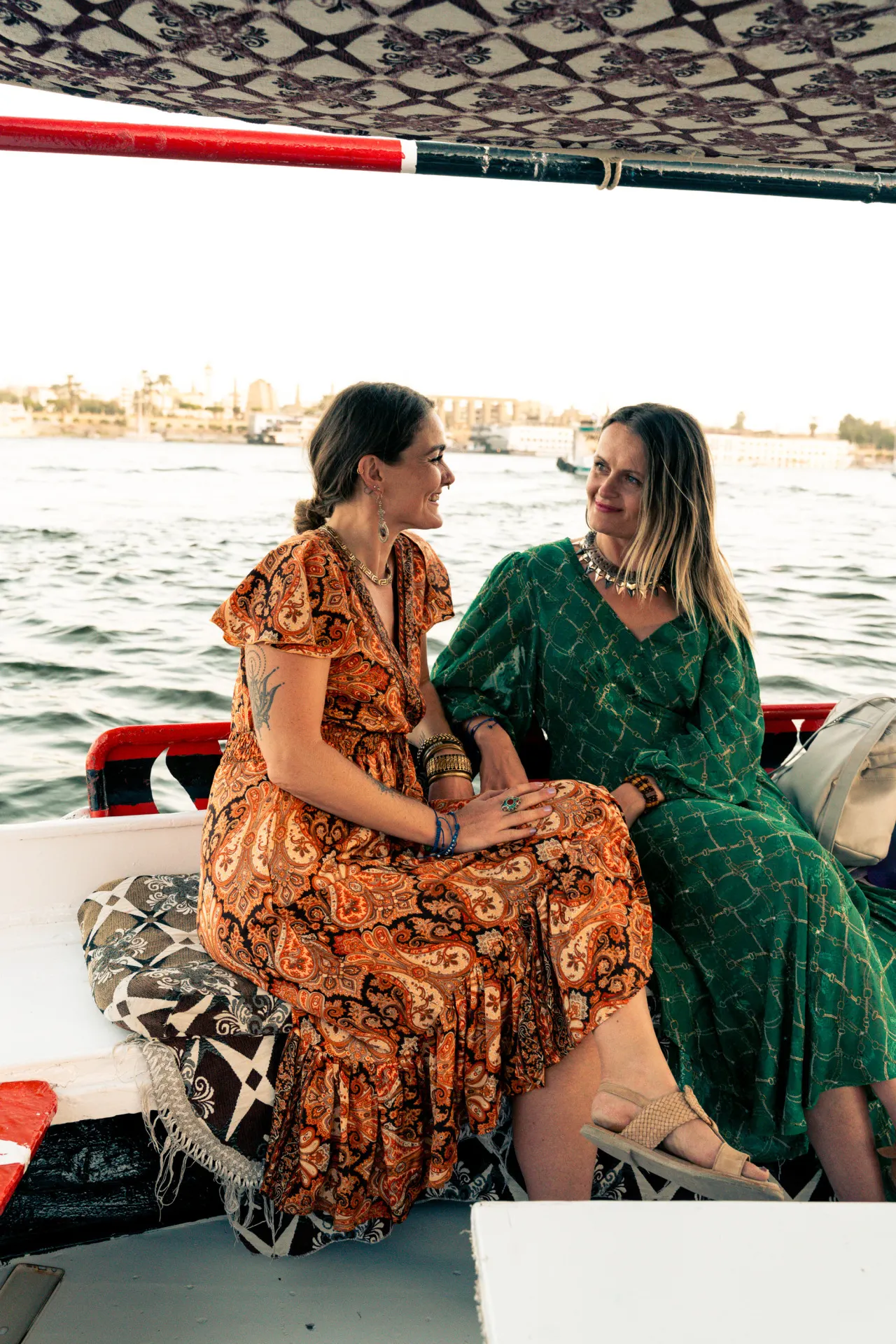 Twee vrouwen in kleurrijke jurken op een boot op de rivier, Egypte