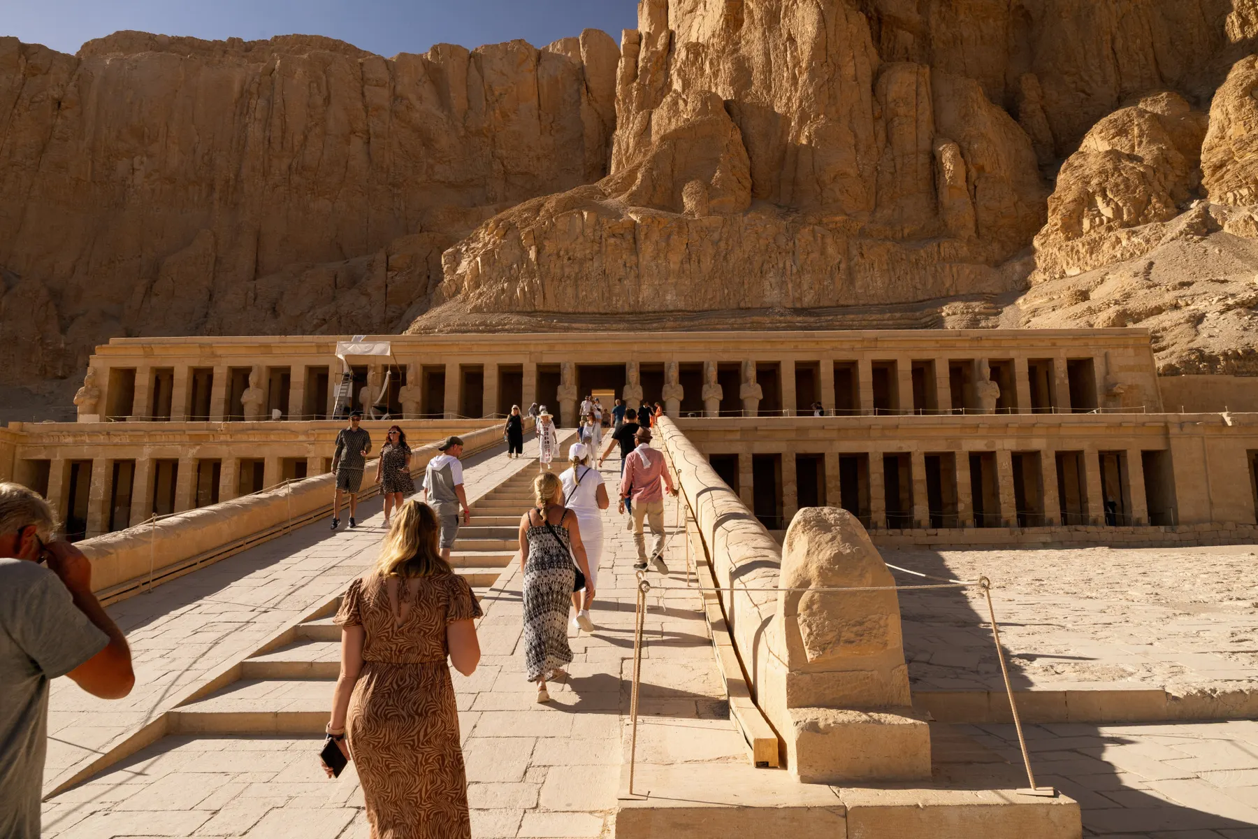Bezoekers lopen naar een tempel die in de rotswand is gebouwd, Egypte