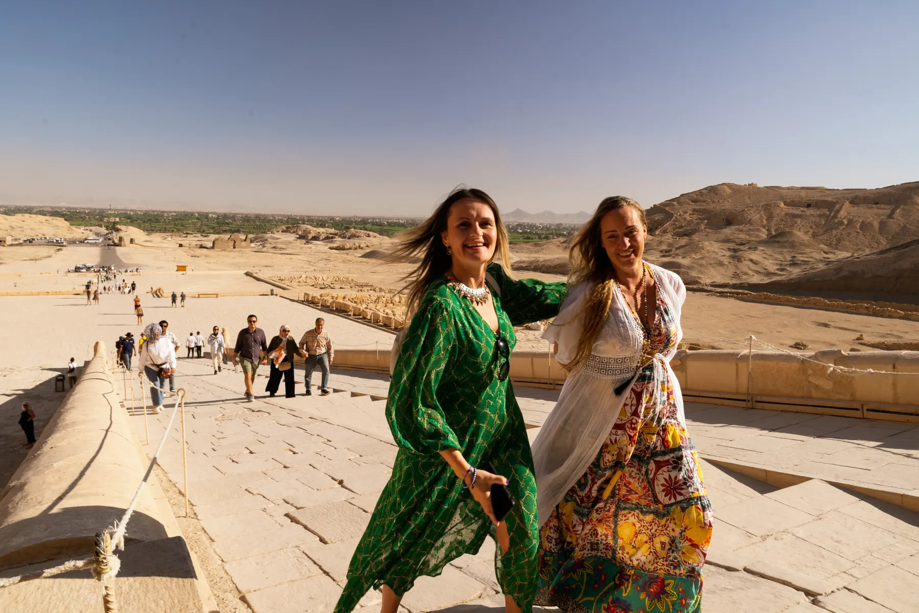 Twee vrouwen in kleurrijke jurken wandelen bij een tempel in Egypte