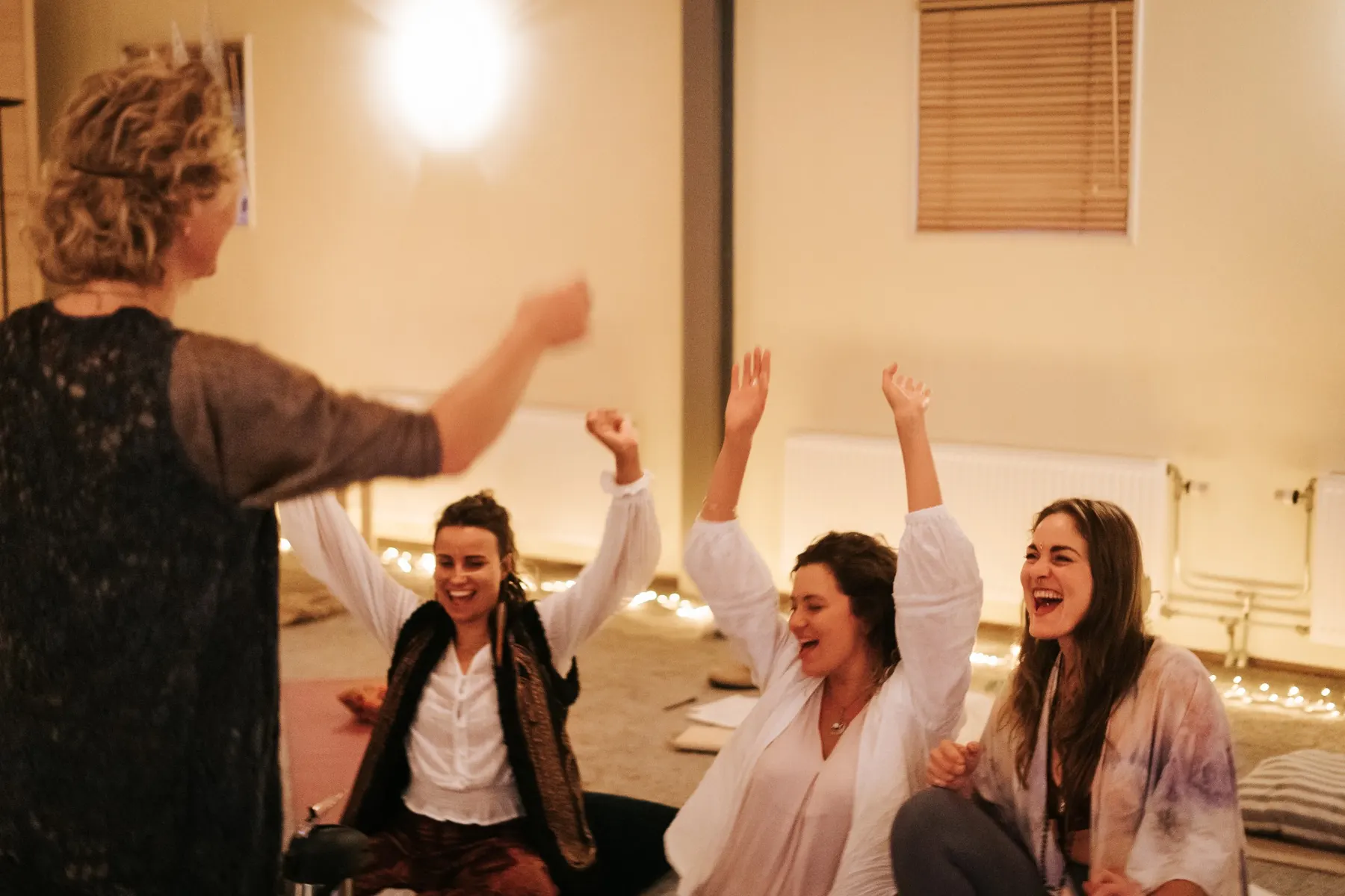 Vrouwen juichen met de armen omhoog in een cirkel bij kaarslicht