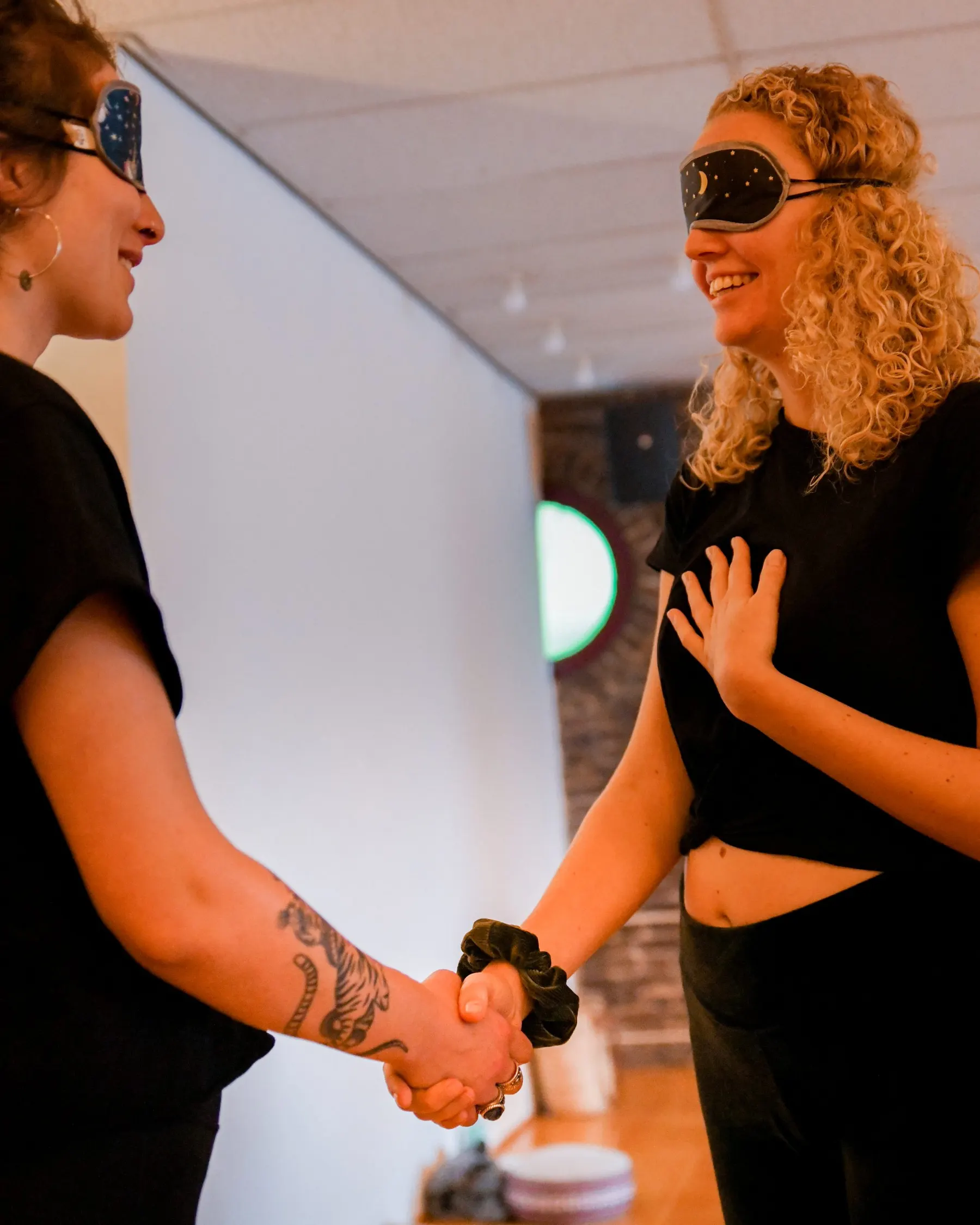 Twee vrouwen met oogmaskers geven elkaar een hand tijdens een oefening