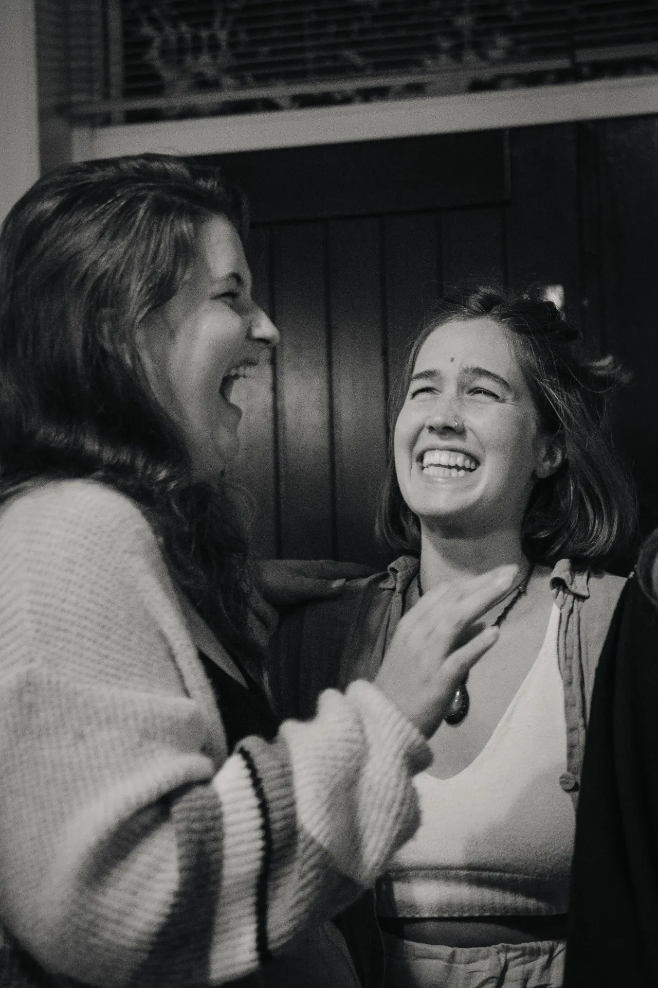 Twee vrouwen lachen samen, in zwart en wit