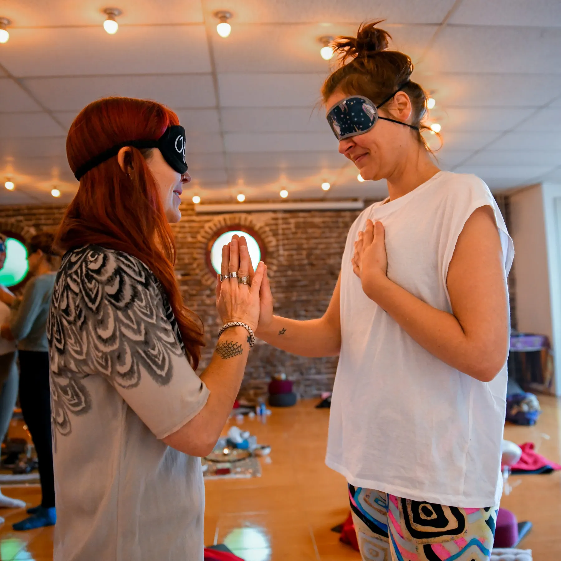 Twee vrouwen met oogmaskers tegenover elkaar, de handen tegen elkaar
