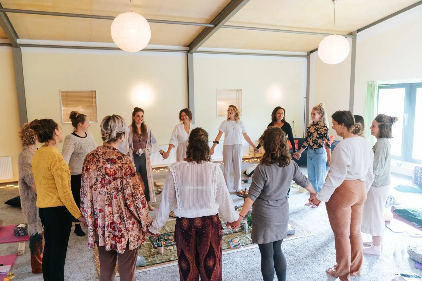 Een kring vrouwen staat samen in een lichte zaal