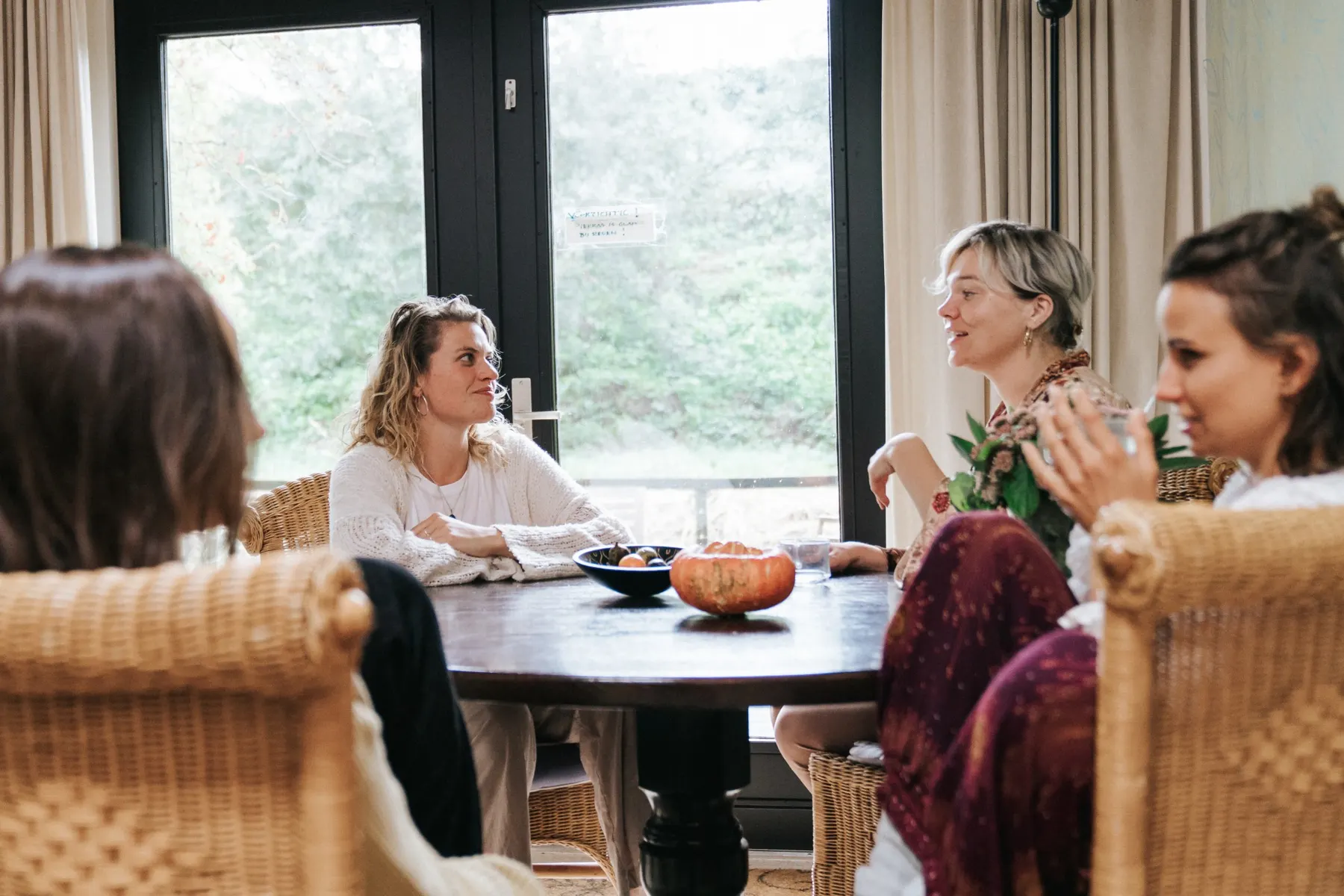 Vrouwen in gesprek aan een ronde tafel bij grote ramen